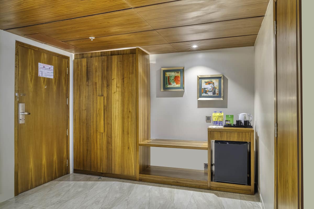 A room with wooden doors, a small kitchenette, and two framed pictures on the wall.