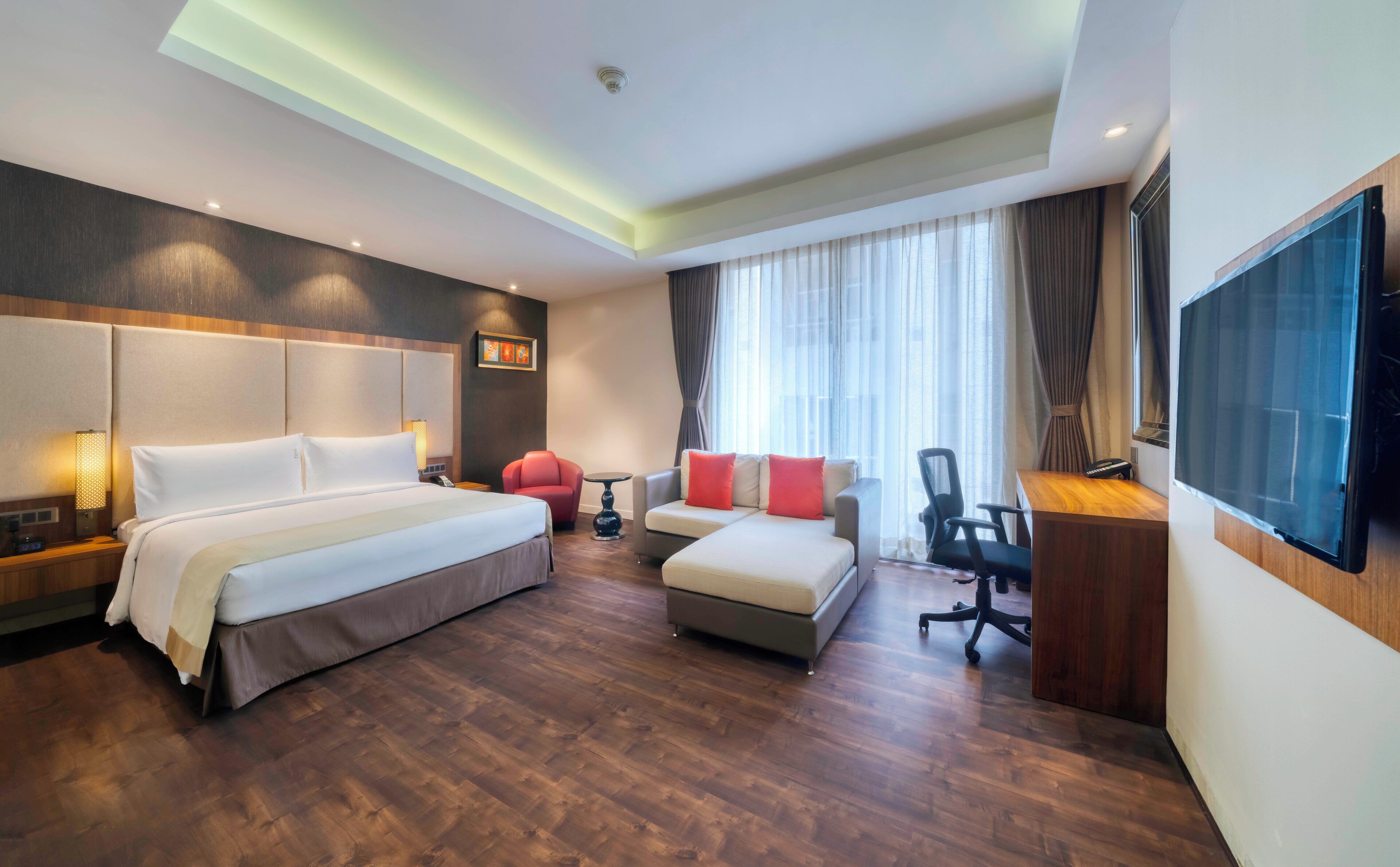 Una habitación de hotel con cama, sofá, escritorio y televisor.