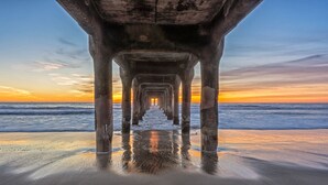 A pier extending into the ocean with a sunset in the background. - Cambria Hotel LAX (El Segundo)