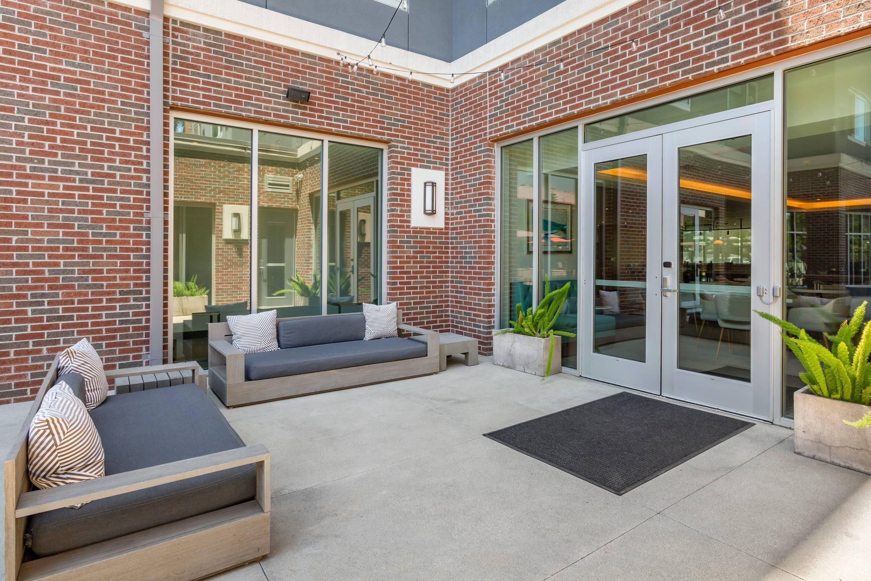 A patio area with a brick wall, glass doors, and outdoor seating.