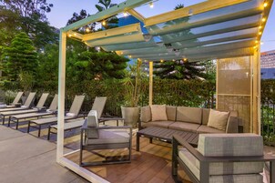 An outdoor patio with lounge chairs, a sofa, and a pergola with string lights.