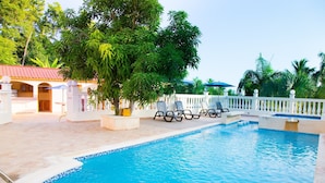 Una piscina con sillas de descanso y una cerca blanca.