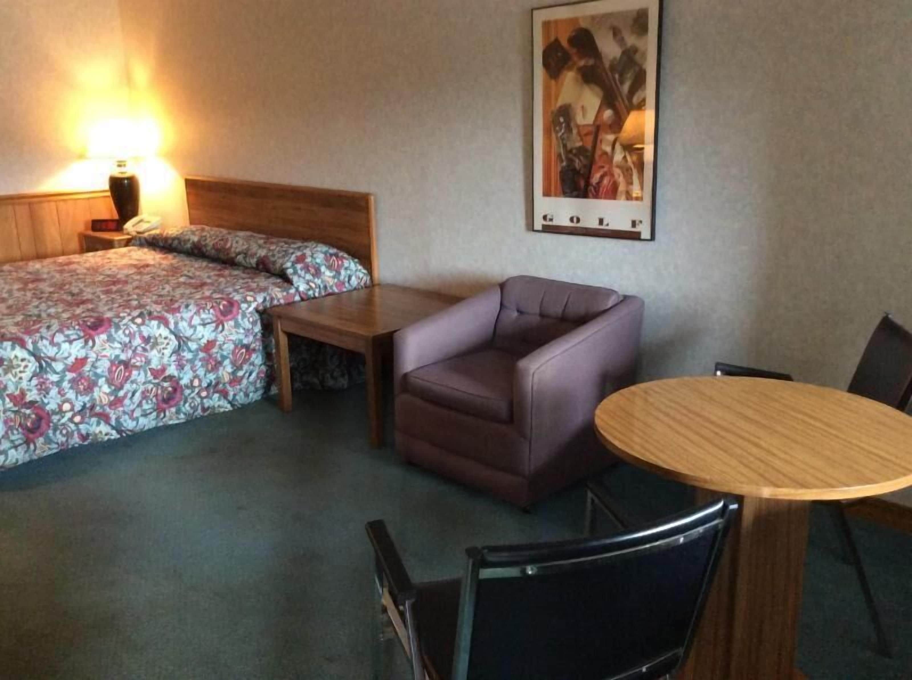 Una habitación de hotel con cama, sofá, una mesita y una mesa de comedor con sillas.