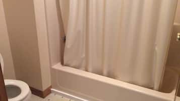 Un baño con inodoro, bañera y cortina de ducha.