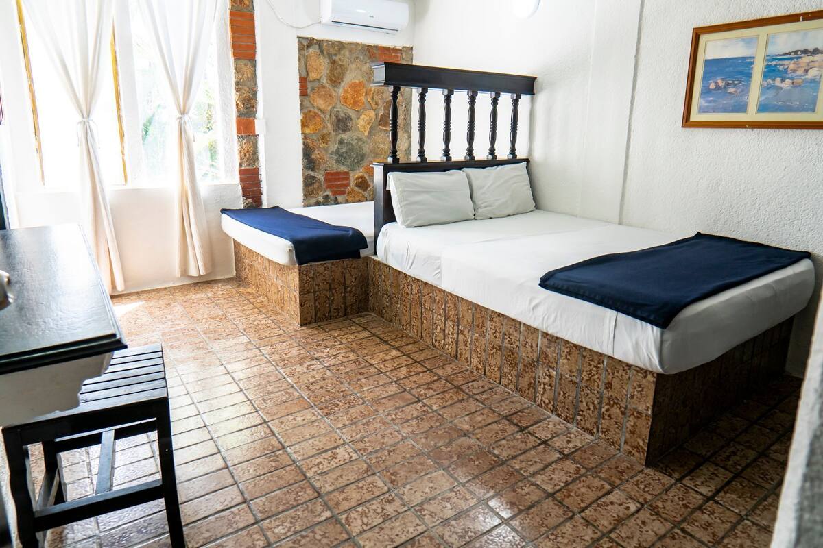 A small, compact room with a bed, a bench, and a table.