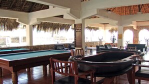 Una mesa de billar con sillas alrededor, un jacuzzi y un comedor con mesas y sillas.