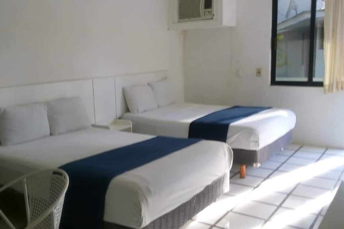 A hotel room with two beds, a chair, and a window.
