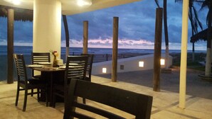 Un área de comedor al aire libre con vista al océano al anochecer.