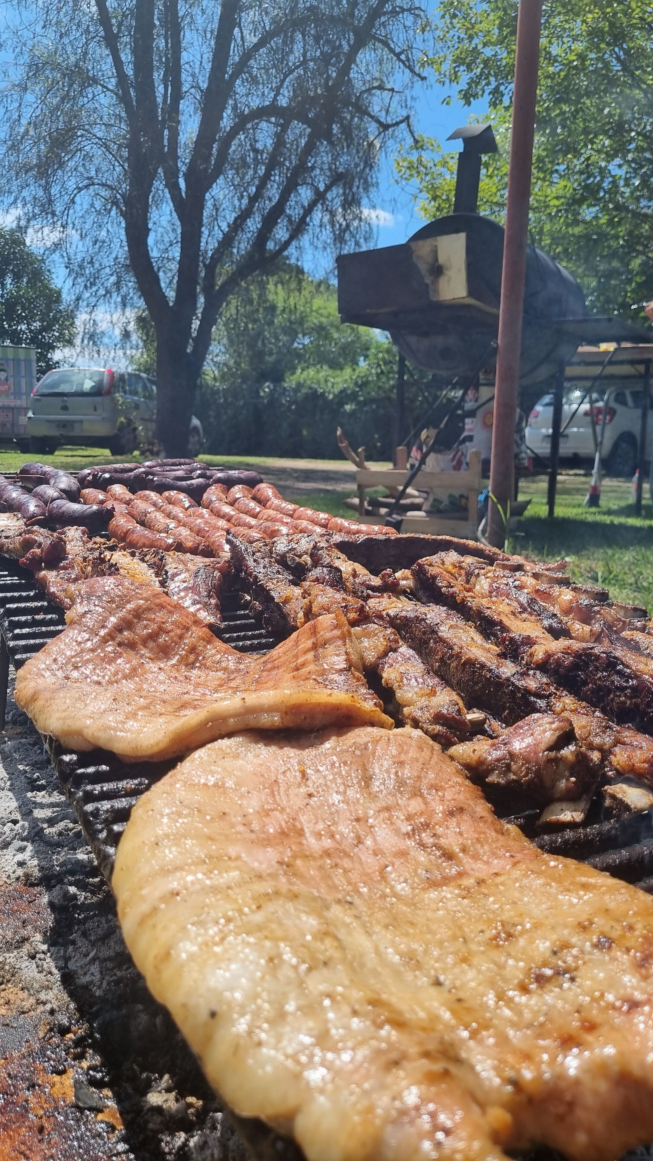 A barbecue with various meats and a large flatbread grilling outdoors.