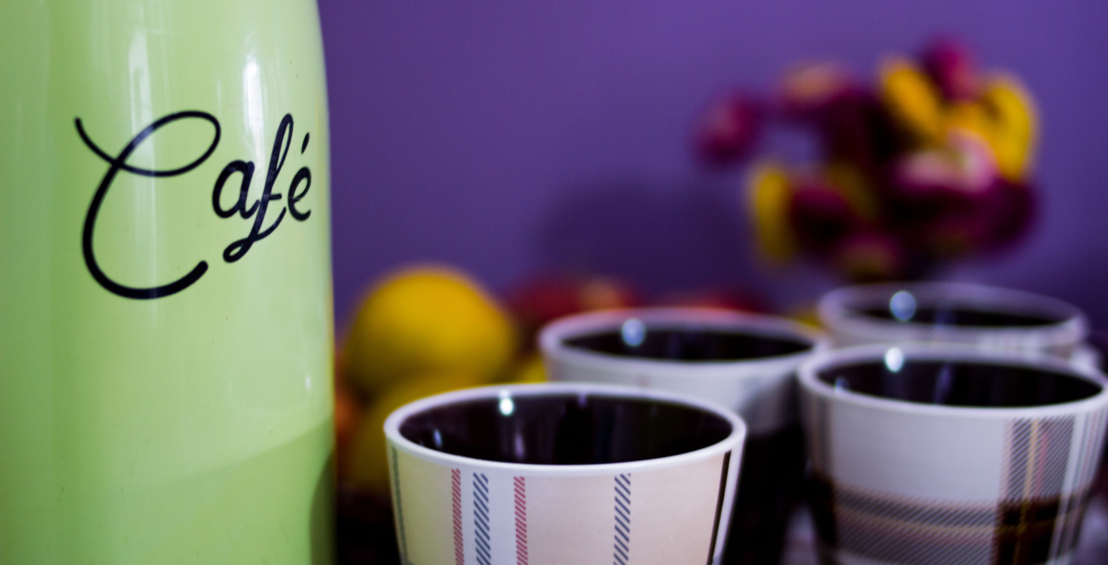 Un contenidor verd amb la paraula “Café”, envoltat de diverses tasses amb dibuixos a ratlles.