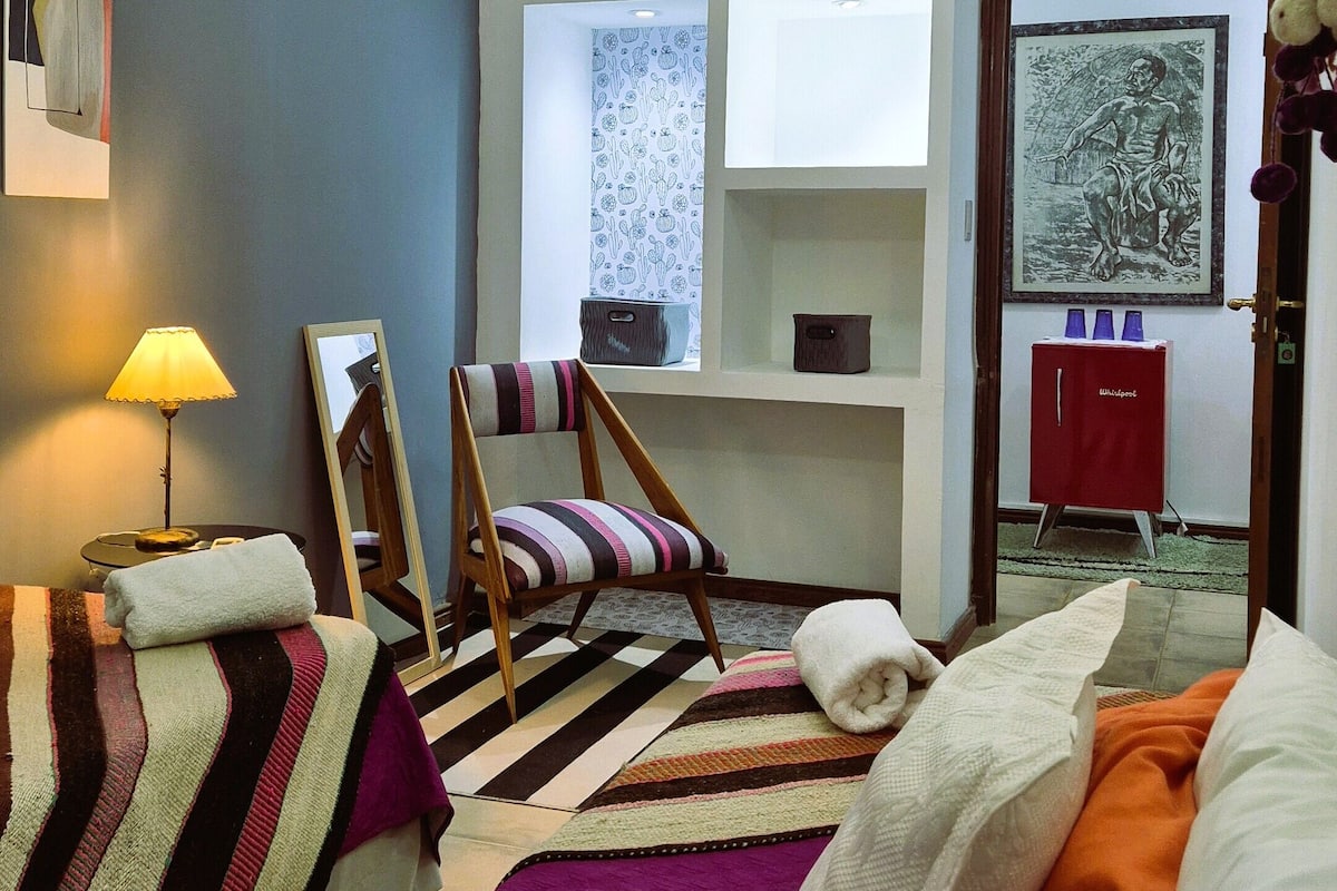 A bedroom with a bed, a chair, a dresser, and a window.