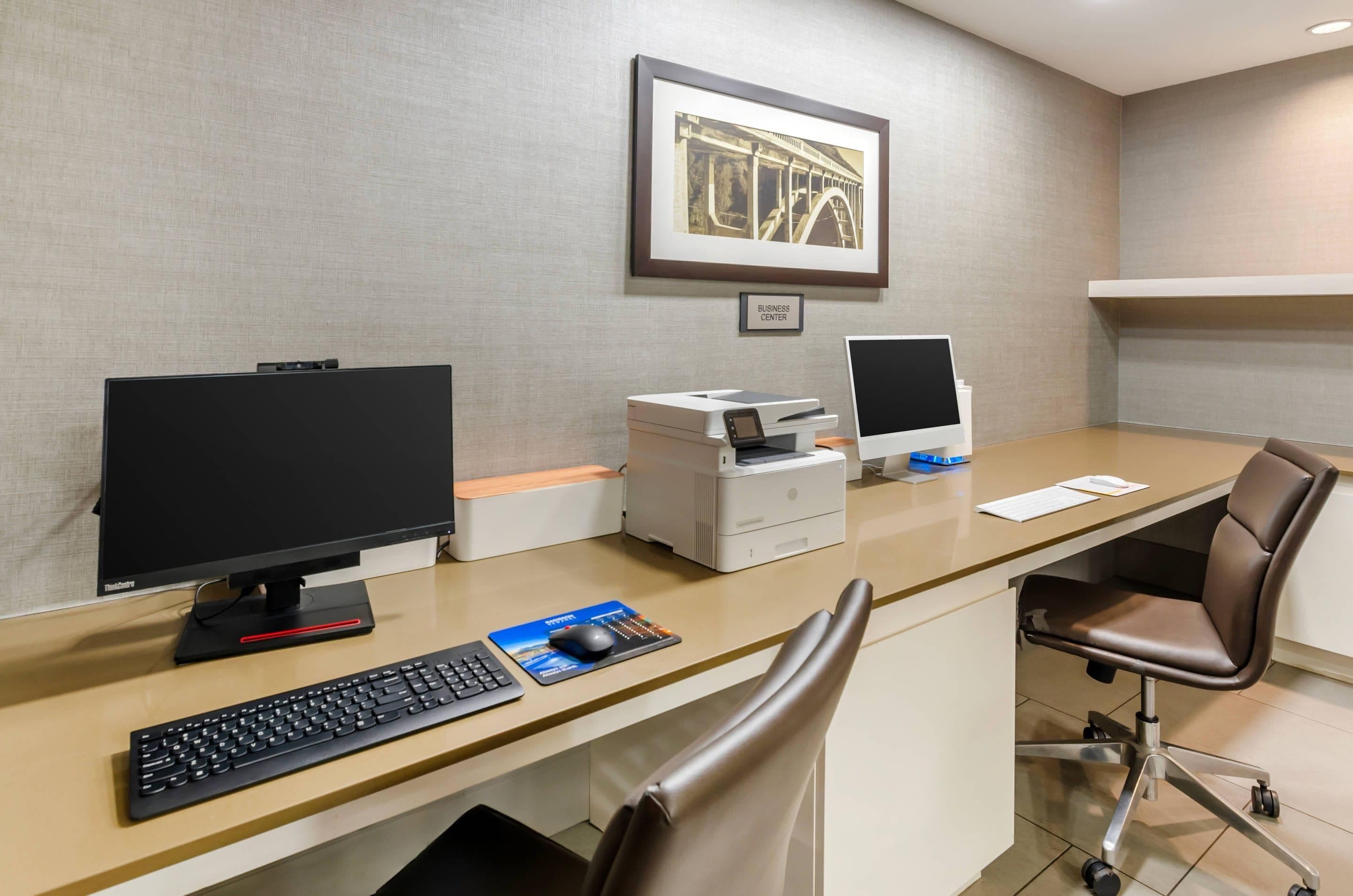Un espace de bureau moderne comprenant un bureau, un ordinateur, une imprimante et un fauteuil ergonomique.