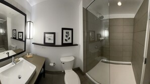 A modern bathroom with a large mirror, a sink, a toilet, and a glass-enclosed shower area.