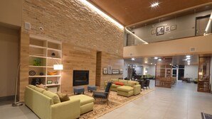 A spacious lobby with a high ceiling, wooden wall panels, and a seating area with sofas and a coffee table. - Country Inn & Suites by Radisson, Charlottesville-UVA, VA (Charlottesville)