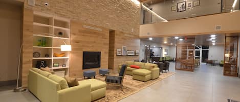 A spacious lobby with a high ceiling, wooden wall panels, and a seating area with sofas and a coffee table.
