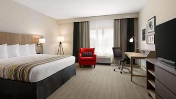 Een hotelkamer met een bed, een bureau, een stoel, een televisie en een raam met gordijnen.
