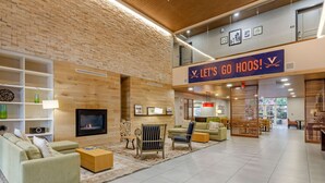 A spacious lobby with a fireplace, seating area, and a sign that reads "LET'S GO HOOS!". - Country Inn & Suites by Radisson, Charlottesville-UVA, VA (Charlottesville)