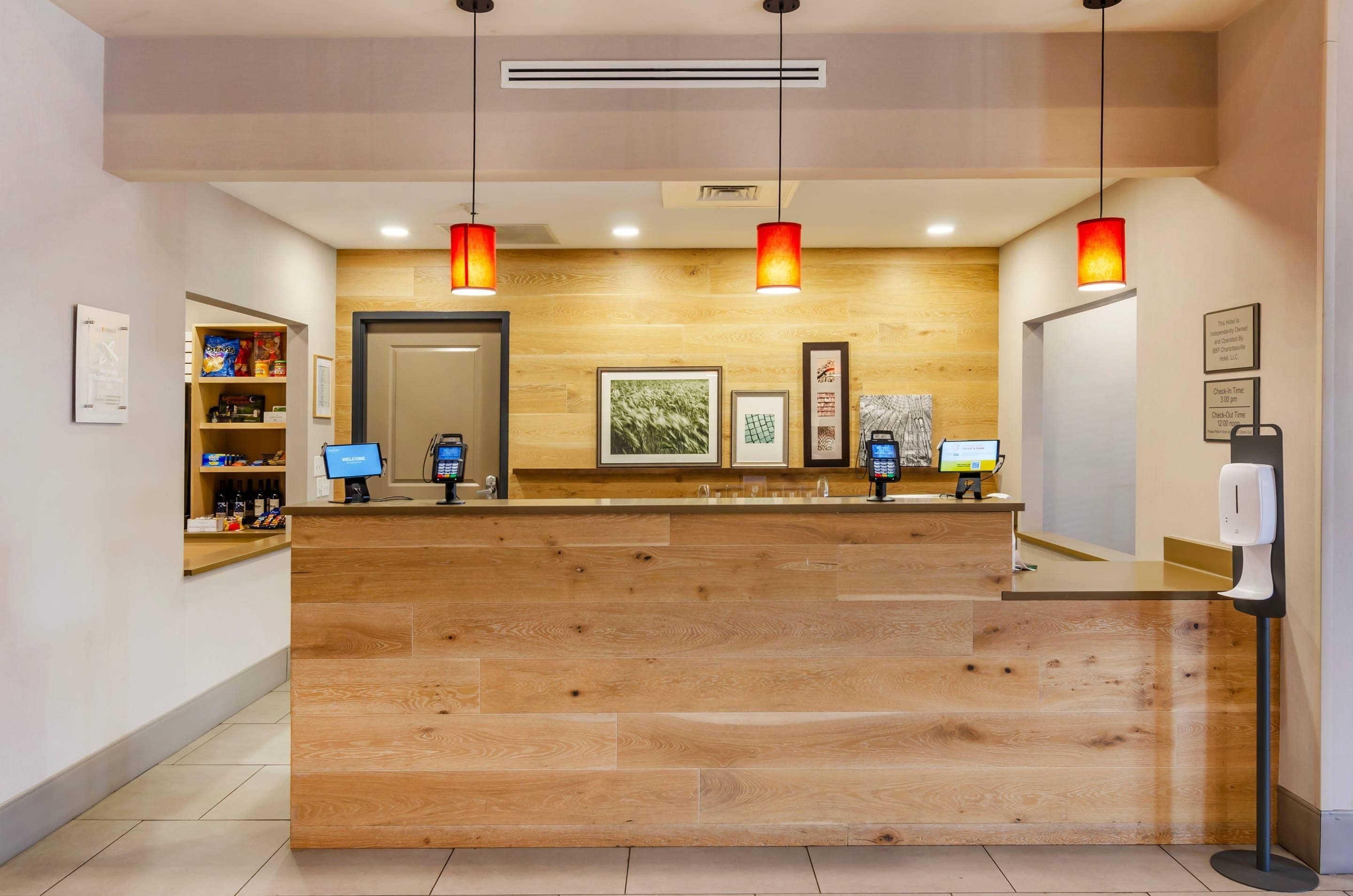 A reception desk with a wooden finish, a digital check-in kiosk, and a wall-mounted information board.