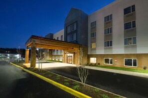 Un hotel de varios pisos con un acceso cubierto, estacionamiento y un césped bien cuidado.