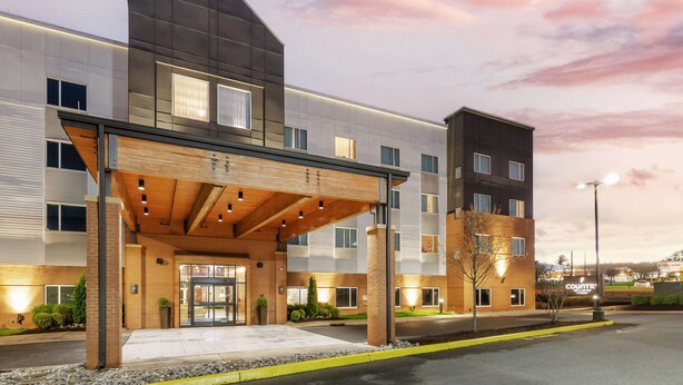 A modern hotel with a covered entrance, multiple floors, and a well-lit facade. - Country Inn & Suites by Radisson, Charlottesville-UVA, VA (Charlottesville)