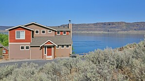 A two-story house with a garage, a dock, and a view of a lake and mountains.