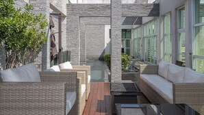 A covered outdoor area with wicker furniture, a small pool, and large windows. - Hotel Cadoro Sao Paulo (São Paulo)