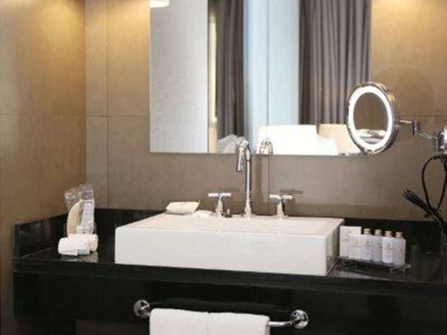 A modern bathroom with a black vanity, white sink, and two wall-mounted lamps.