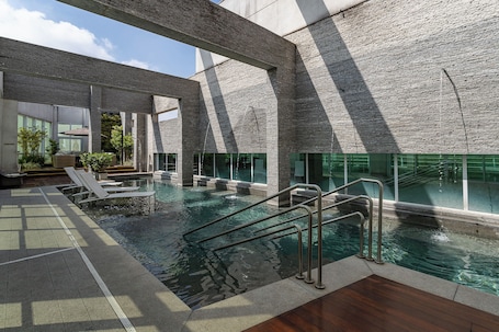 Una piscina al aire libre, sillones reclinables de piscina