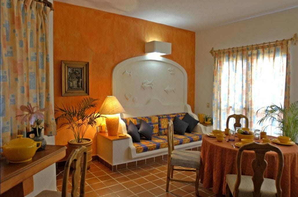Una habitación acogedora con un sofá, una mesa de comedor para dos personas y un cabecero decorativo.