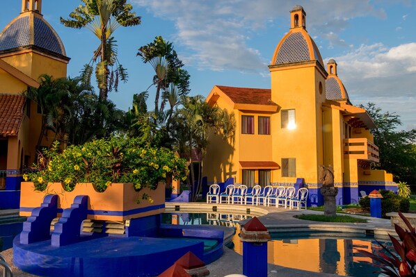 A yellow building with blue accents and a pool area.