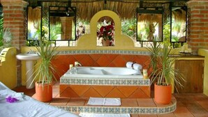A bathroom with a bathtub, sink, and potted plants.