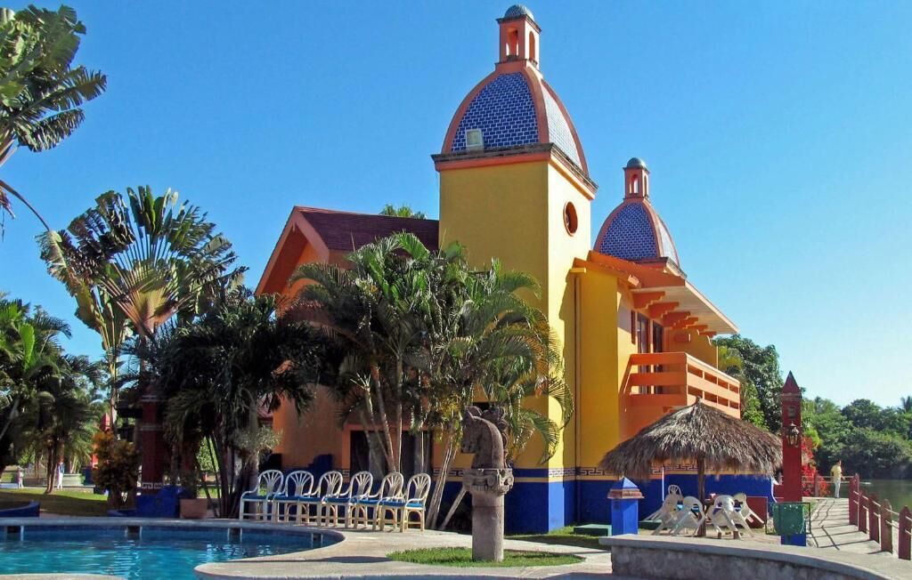 A resort with a pool, palm trees, and a building with a blue and yellow facade.