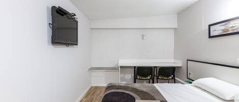 A small, modern room with a bed, a desk, and a chair.