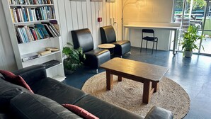Een moderne woonkamer met een leren bank, een houten salontafel, een boekenkast en een eethoek met stoelen.