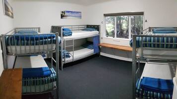 Un dormitorio con literas, una ventana que da a árboles y un escritorio pequeño.