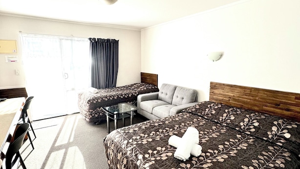 Habitación de hotel con una cama grande, un sofá, una mesita y una silla.