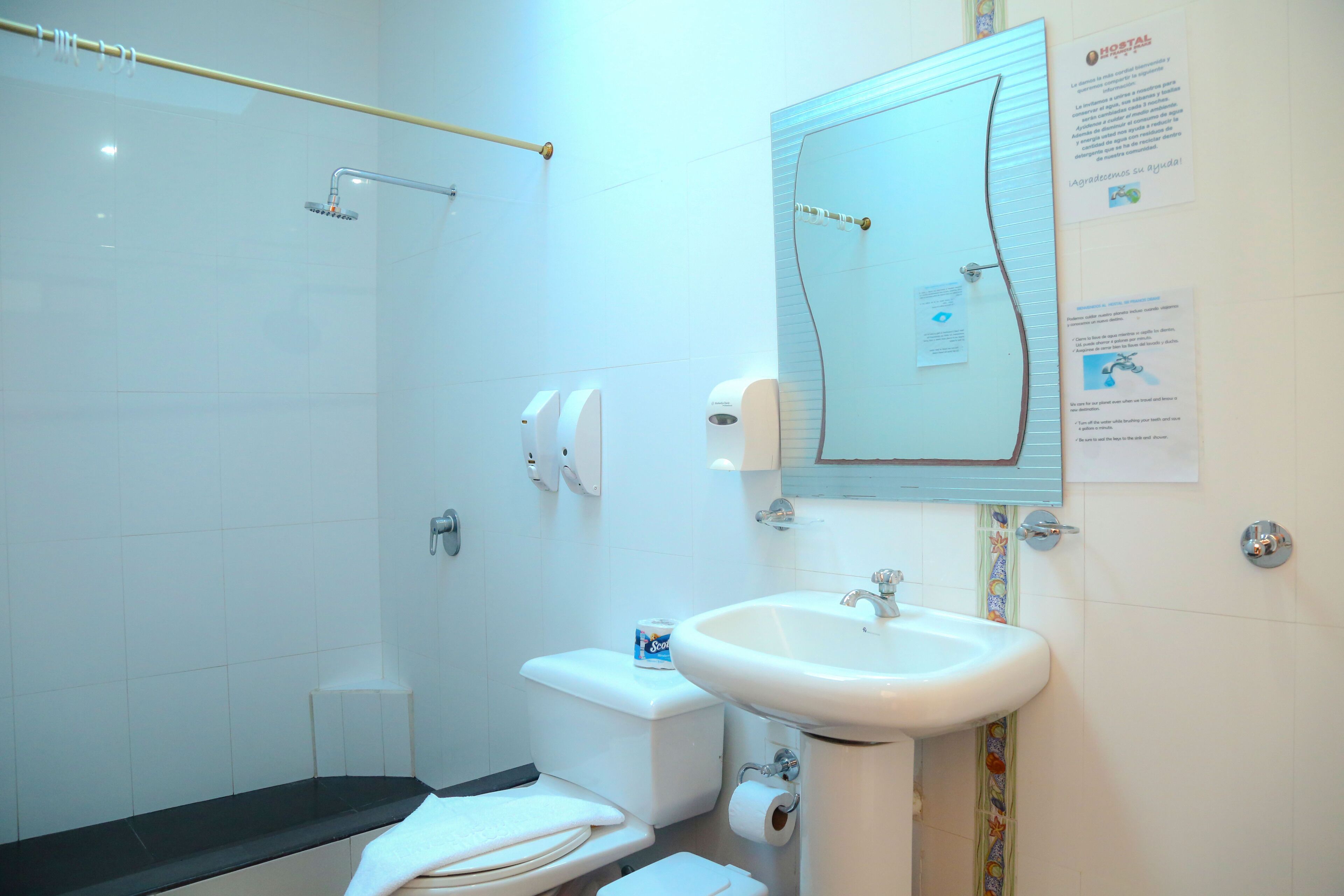 A bathroom with a shower, toilet, sink, and towel rack.