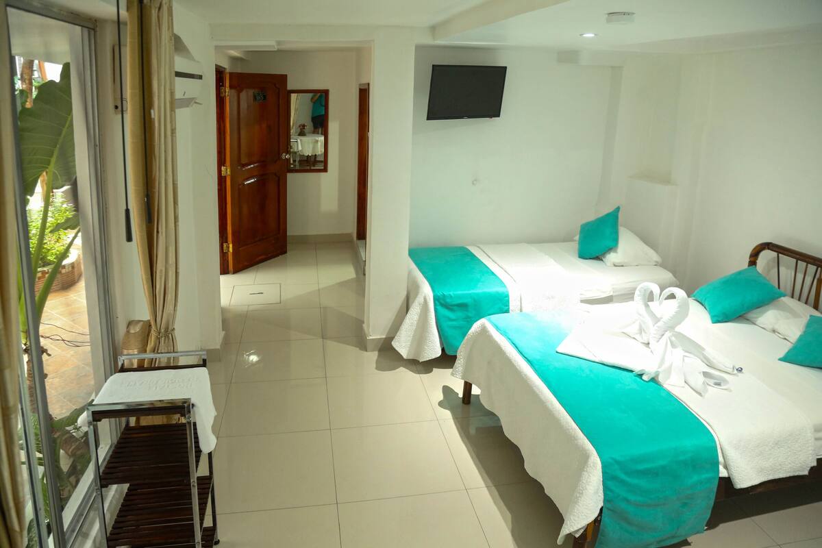 Quarto de hotel com duas camas, uma TV fixada na parede e vista para o exterior.