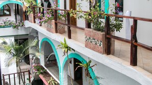 Un edificio de varios niveles con balcones, plantas en macetas y un patio empedrado.