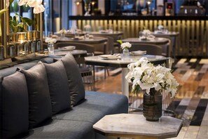 A modern restaurant interior with a sofa, tables, and a vase of white flowers. - Glad Live Gangnam (Seoul)