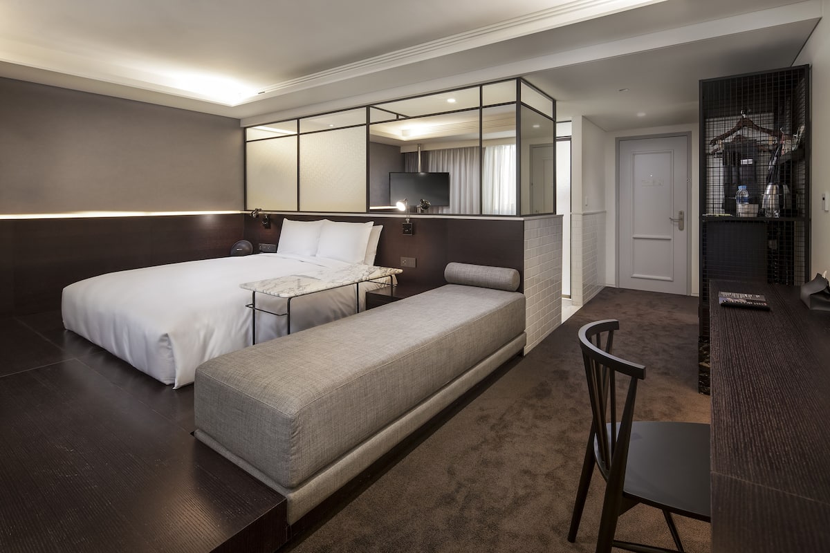 A hotel room with a bed, a sofa, a desk, and a TV.