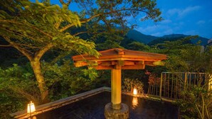 Une structure de portail torii japonais traditionnel, située dans un jardin paisible, avec un bassin aux eaux calmes et une végétation luxuriante.