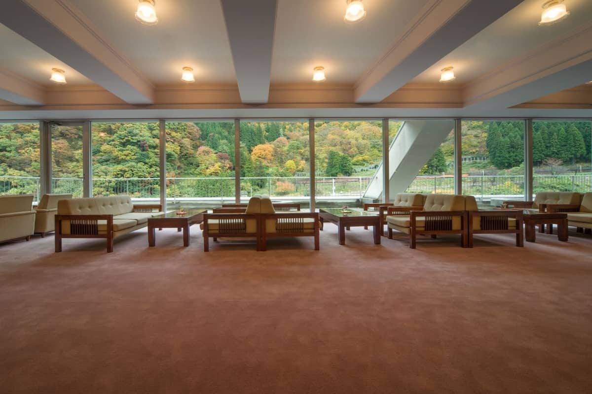 A spacious room with large windows, multiple seating areas, and a high ceiling.