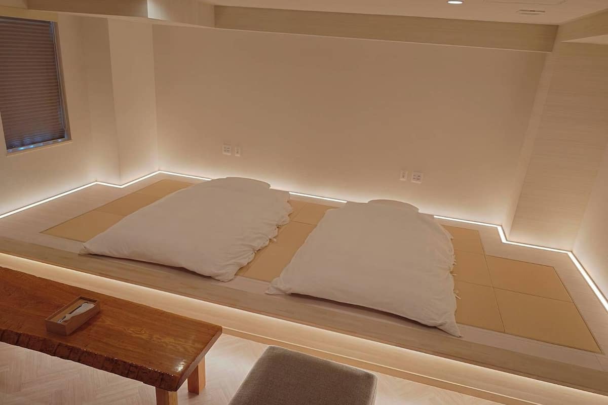 A modern bedroom with a bed, bedside table, and bench.