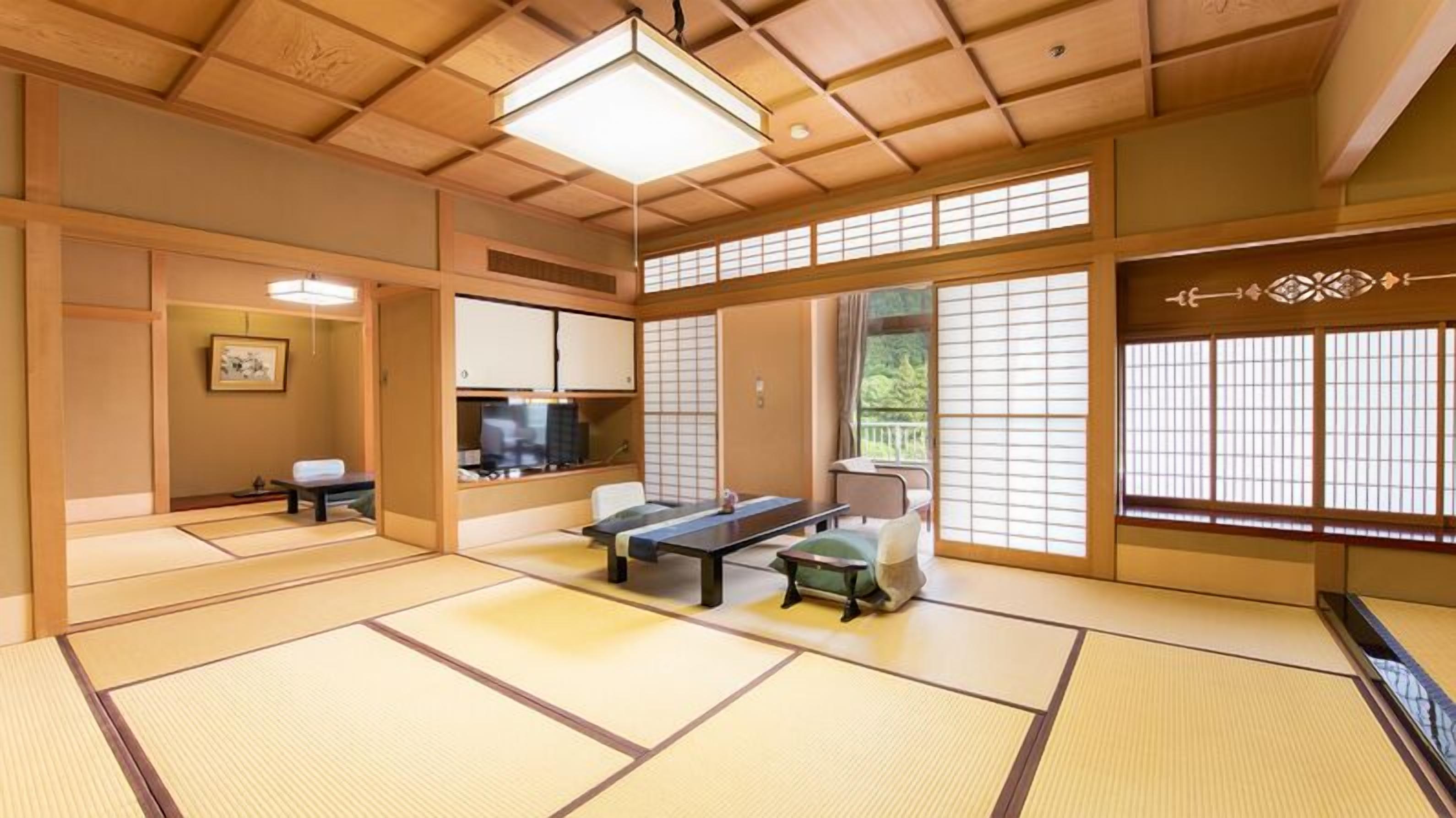 A traditional Japanese room with tatami flooring, a low table, a sofa, sliding doors, and a television.