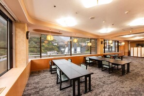 A conference room with tables and chairs, large windows with a view, and a carpeted floor. - Hotel Kurobe (Kurobe)