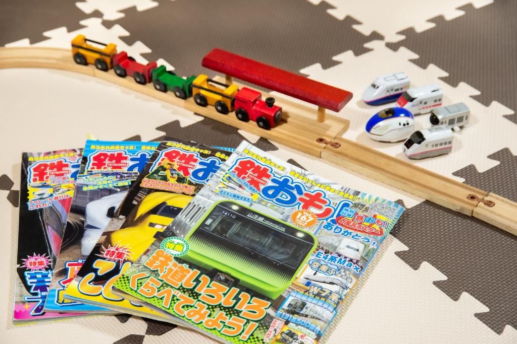 A toy train set with miniature trains and tracks, surrounded by colorful magazines.