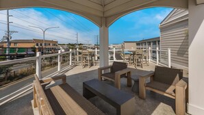 A covered outdoor seating area with wicker furniture and a view of the street. - Atlantic Oceanside Dewey (Dewey Beach)