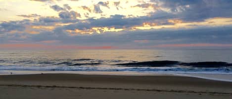 A beach with a wide sandy shore and waves approaching the beach.