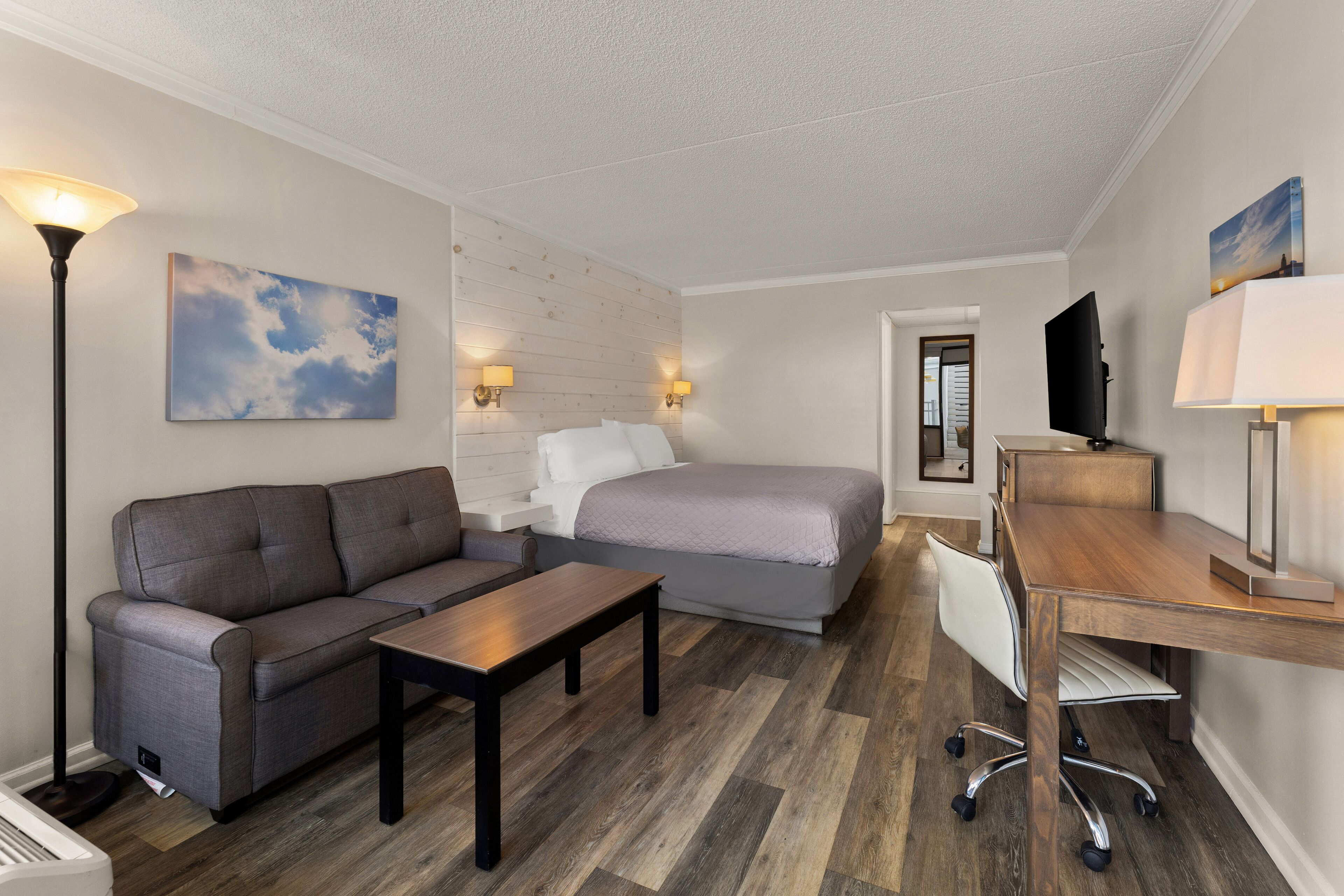 Une chambre d’hôtel avec un canapé, un lit, un bureau et une télévision.